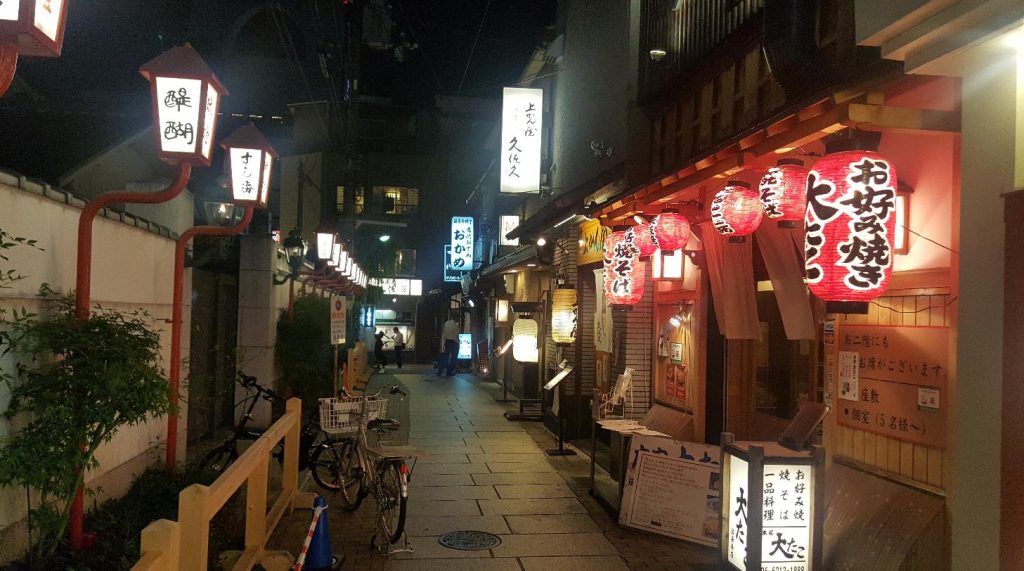 Red lanterns lining the narrow paved alley of Hozenji Yokocho in Osaka at night